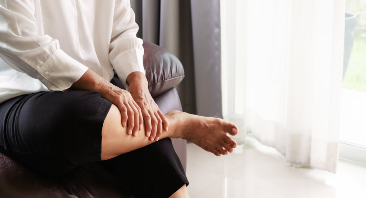 Leg cramp, senior woman suffering from leg cramp pain at home